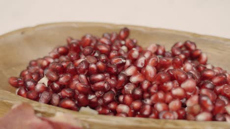 rack focus of pomegranate seeds inside of wooden plate juicing and using fresh ingredients and fresh whole pomegranates