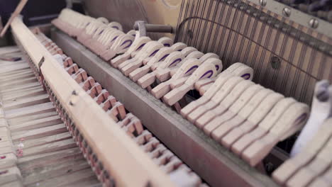 closeup of inside ancient piano hammers hitting strings