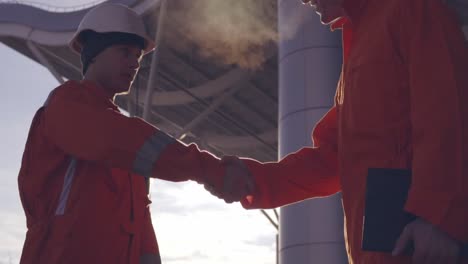 Close-Up-view-of-two-construction-workers-in-orange-uniform-and-hardhats-shaking-hands-at-the-building-object