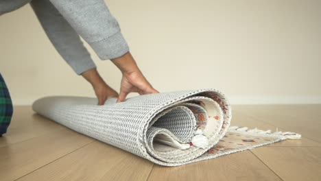 person rolling up a colorful patterned rug