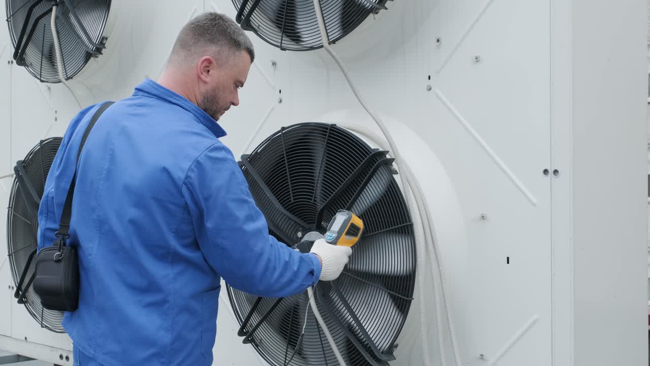 Technician uses a thermal imaging infrared thermometer to check the condensing unit heat exchanger