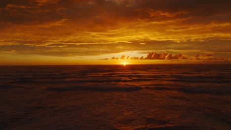 reverse aerial view of stunning golden sunset with dramatic cloudy sky and the tasman sea at pancake rocks on the wild west coast of south island in new zealand aotearoa