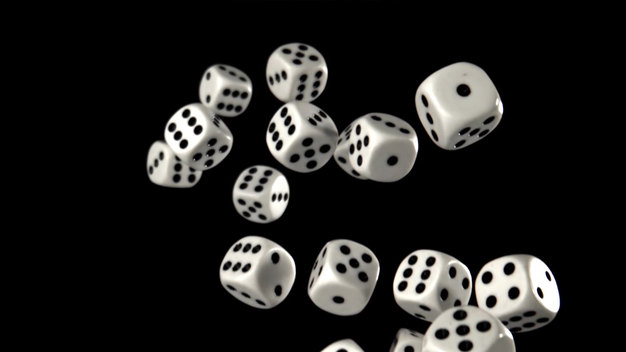 Slowmotion hvide terninger falder og hopper på sort baggrund