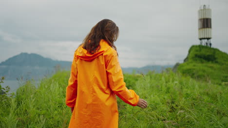 woman in orange raincoat hiking in nature