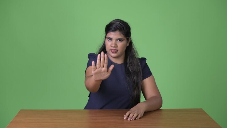 Young overweight beautiful Indian businesswoman against green background
