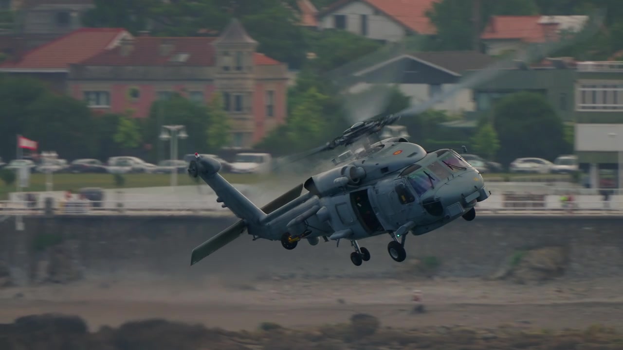 SH-60 Seahawk della Marina Spagnola a bassa quota sopra la spiaggia rocciosa di Gijon durante uno spettacolo aereo.