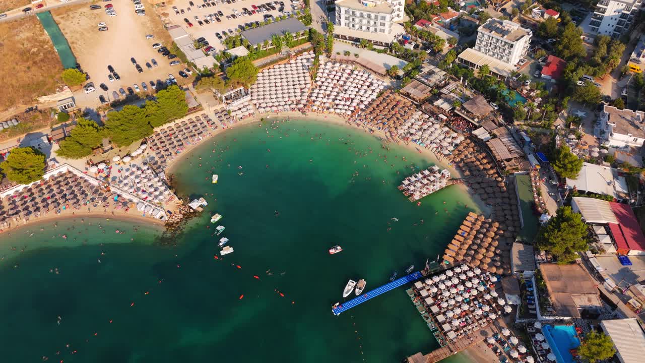 Ksamil beach in albania with tourists swimming and sunbathing in a vibrant setting, aerial view