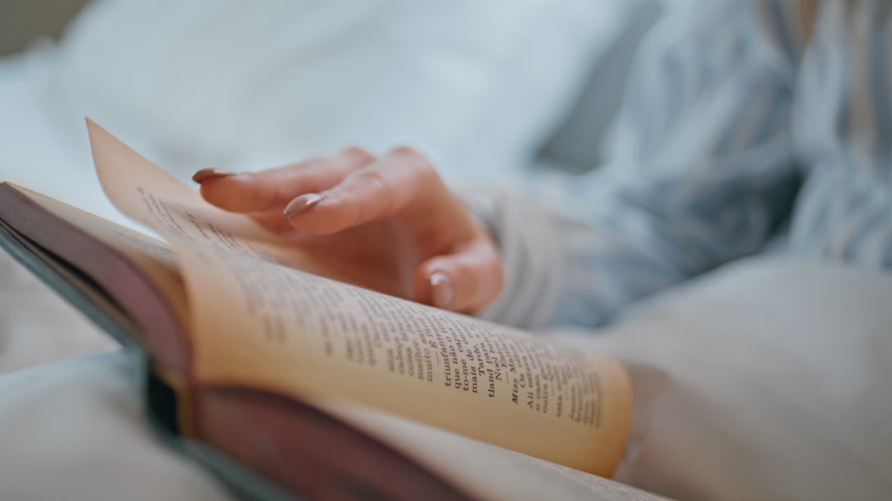 Woman hands touching pages with romantic novel lying apartment bed closeup