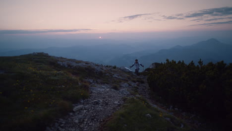 Hiker-climbing-with-the-hiking-poles-up-a-hill-towards-the-camera-in-the-early-morning