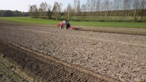 aerial established shot of red tractor preparing the land farm