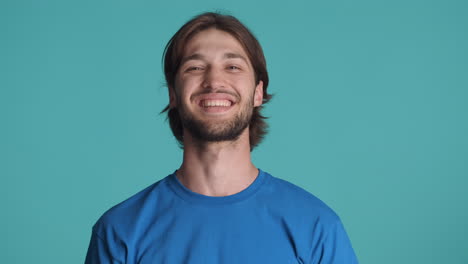 hombre feliz caucásico frente a la cámara sobre un fondo azul.