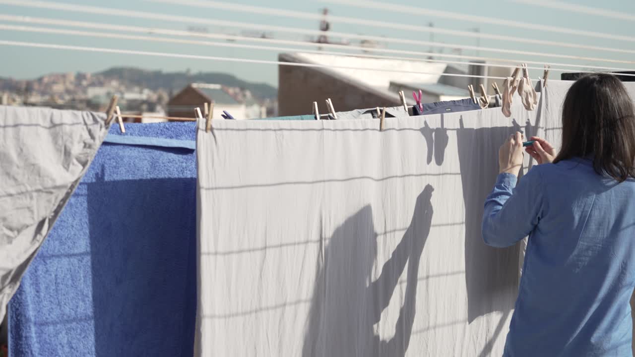 지붕에 있는 옷줄에 은 옷을 매달고 있는 여자.