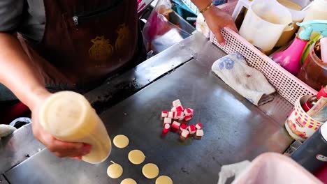 vendor preparing crab stick pancakes on a griddle