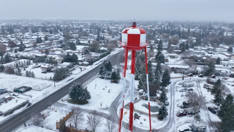 Vista-Aérea-De-Una-Torre-De-Agua-Que-Se-Eleva-Sobre-El-Suelo-Cubierto-De-Nieve