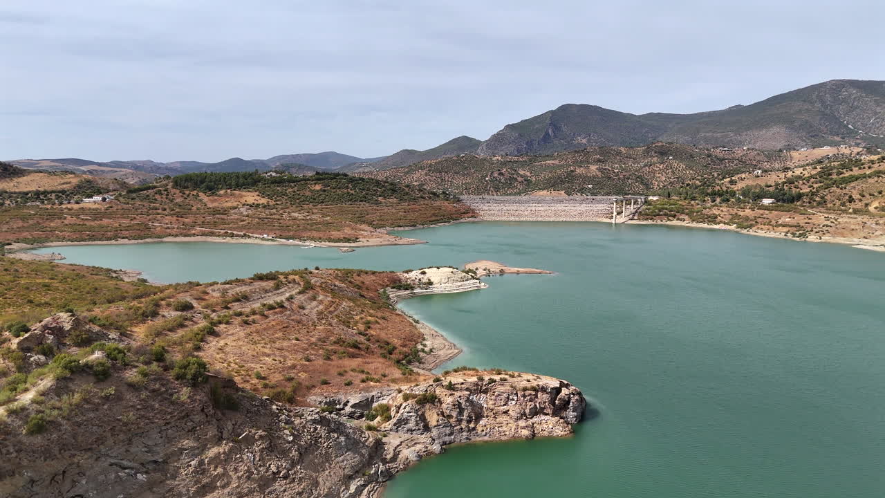 Aerial drone footage of Zahara-El Gastor lake and surrounding mountains in Andalusia, southern Spain, under clear blue sky