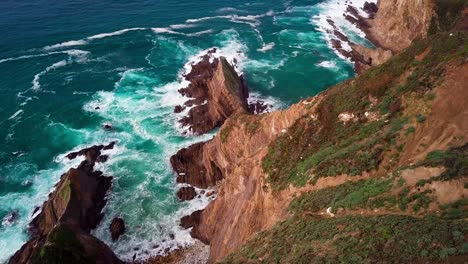 view from top of huge cliff with breaking ocean waves in big sur, cali