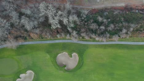 vista aérea de 4k a lo largo de la frontera de un campo de golf junto a árboles marrones verdes