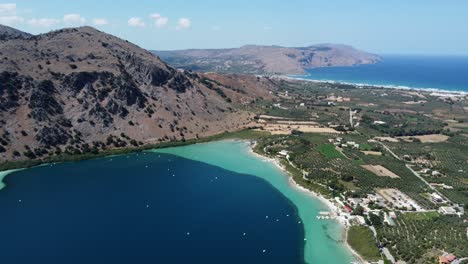 kournas freshwater turquoise lake in crete, kournas mountainous village on greek island, establishing drone shot