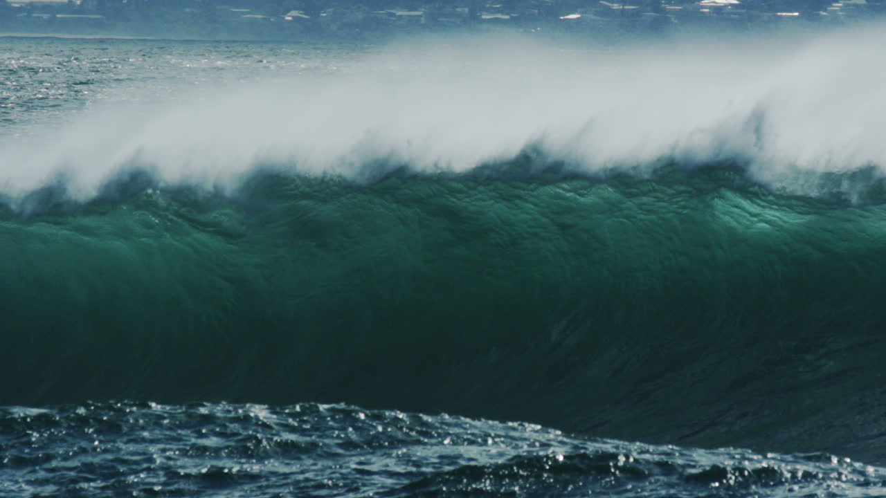 Slow motion shot of rising wave line before breaking into white foam, long lens perspective