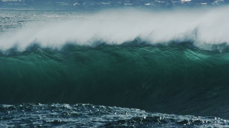 Slow motion shot of rising wave line before breaking into white foam, long lens perspective