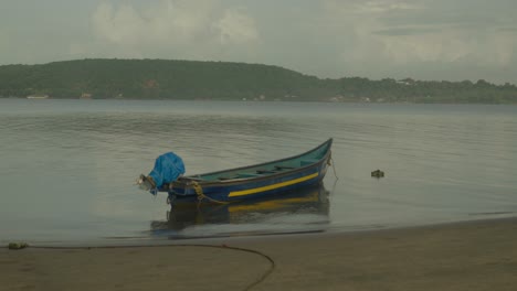 Eine-Totalaufnahme-Fängt-Die-Essenz-Eines-Indischen-Tropischen-Strandes-Ein,-Mit-Einem-Vor-Anker-Liegenden-Fischerboot,-Das-Friedlich-Am-Ufer-Ruht