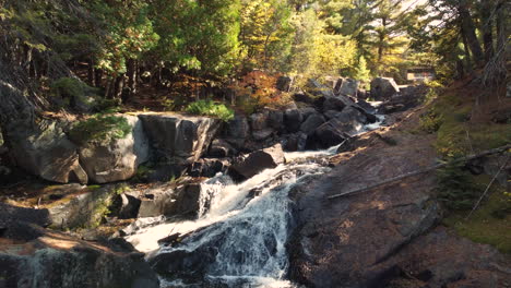 Aerial-forward-view-of-a-stream-in-the-forest-with-small-waterfalls-and-rocks