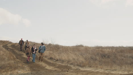 Group-Of-Teenage-Friends-Talking-And-Walking-In-A-Wheat-Field-Path-On-A-Windy-Day