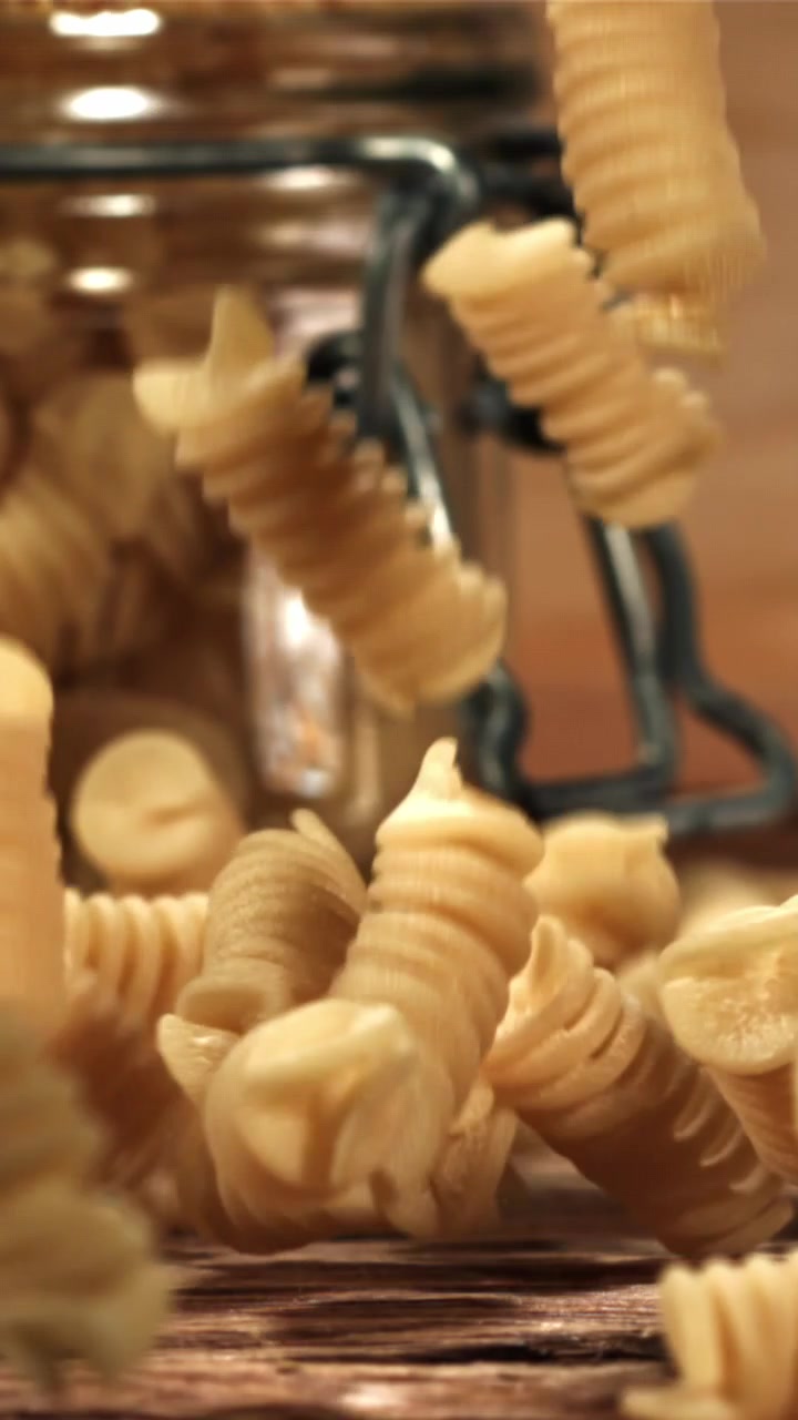 Uncooked Fusilli Pasta Falling in Slow Motion onto a Wooden Table