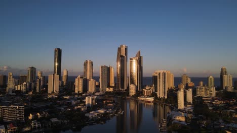 Afternoon-sunset-reflects-against-a-towering-city-skyline-rising-above-an-urban-river-waterway