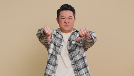 upset asian man guy showing thumbs down gesture disapproval dissatisfied dislike negative feedback