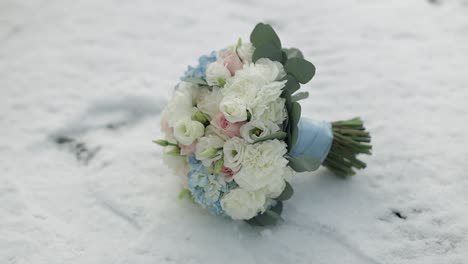 beautiful wedding bouquet with white, pink, and blue flowers in the snow