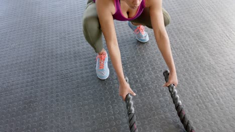 Mujer-Birracial-Inalterada-Enfocada-Haciendo-Ejercicio-Con-Cuerdas-De-Batalla-En-El-Gimnasio,-En-Cámara-Lenta