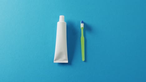 Video-of-close-up-of-toothbrush-and-paste-on-blue-background