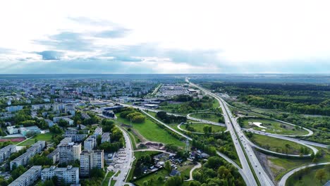 Wide-angle aerial view of Kaunas suburban landscape with a highway cutting through green fields and industrial patches