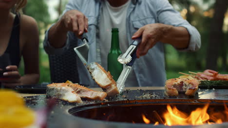 unrecognizable man using tongues and spatula outdoors. chef finishing cooking