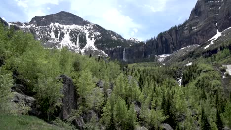 forest area in the rocky mountains with snowed peaks and rocky cliff sides, colorado usa, handheld shot