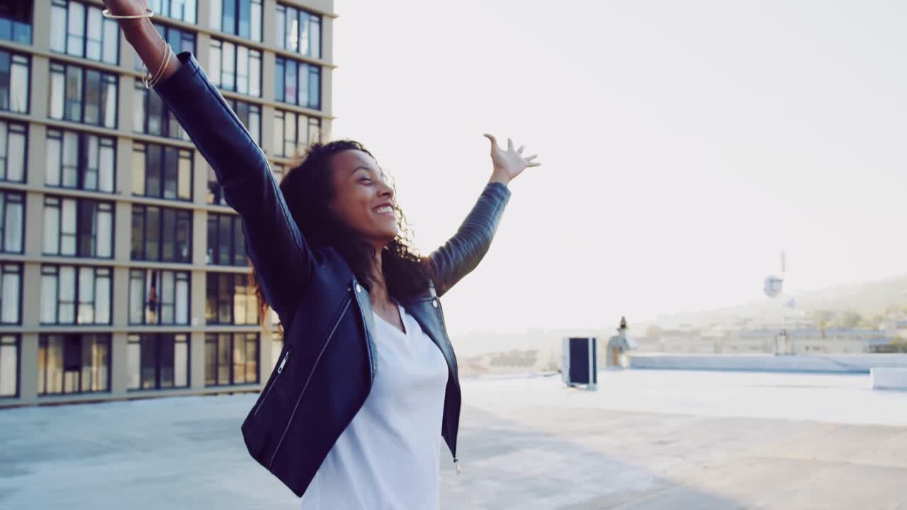 mujer joven de moda en el techo urbano con los brazos extendidos