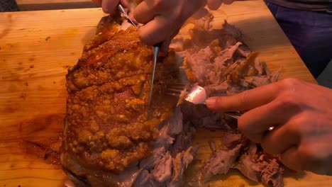 Men-hands-cutting-a-roasting-suckling-pig-with-forks-like-savages,-extra-crispy-skin,-pork-bbq-grill,-wild-behaviour,-4K-static-shot