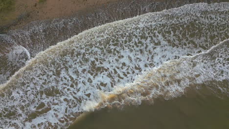 view directly down onto white waves crashing from brown murky irish sea