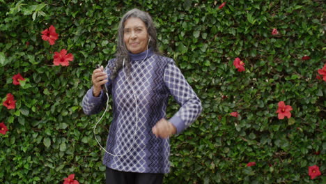 portrait of beautiful elderly indian woman dancing playful enjoying listening to music on earphones in outdoors garden background happy retirement