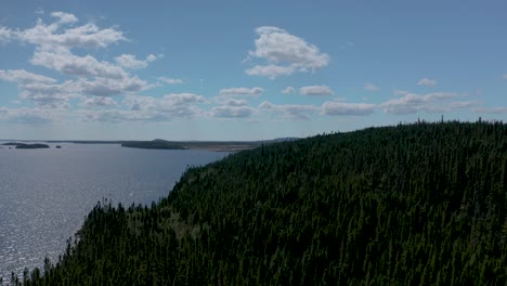drone flying over a forest towards a beautiful lake in northern quebec on a summer day