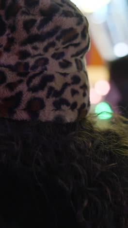 person with leopard print bucket hat and curly hair in a nighttime setting