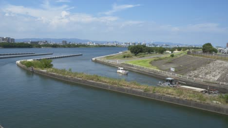 barge and tug boat entering the kema lock gate by yodo river in osaka, japan. - wide shot