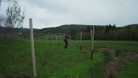 Man-At-Work-Pulling-Out-Wooden-Posts-Of-Fencing-At-The-Field