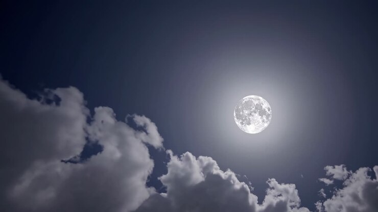 Um vídeo sereno do céu noturno com uma lua cheia brilhando intensamente, cercada por nuvens