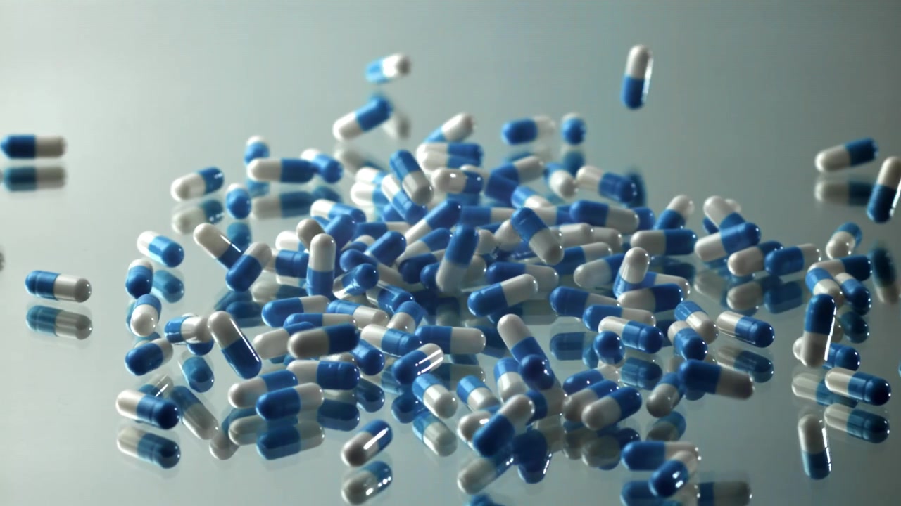 Capsule blu e bianche che cadono su una superficie riflettente