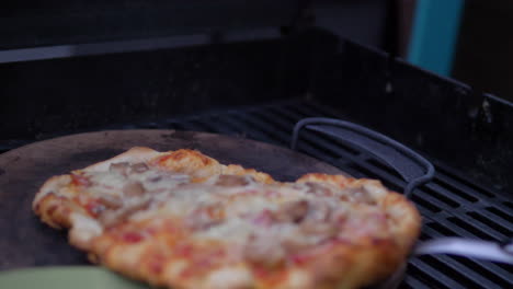 putting a homemade pizza out of a wood fired pizza grill oven