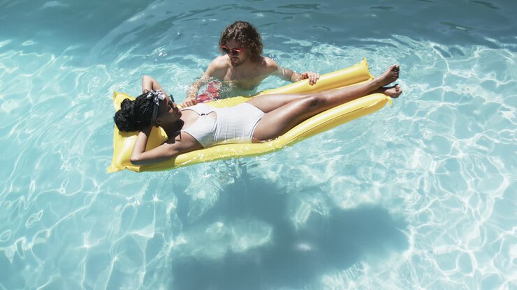 Diverse couple, a young African American woman and a young Caucasian man, enjoy a pool day