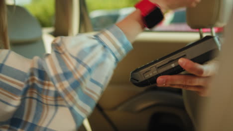 woman using a contactless payment terminal in a car