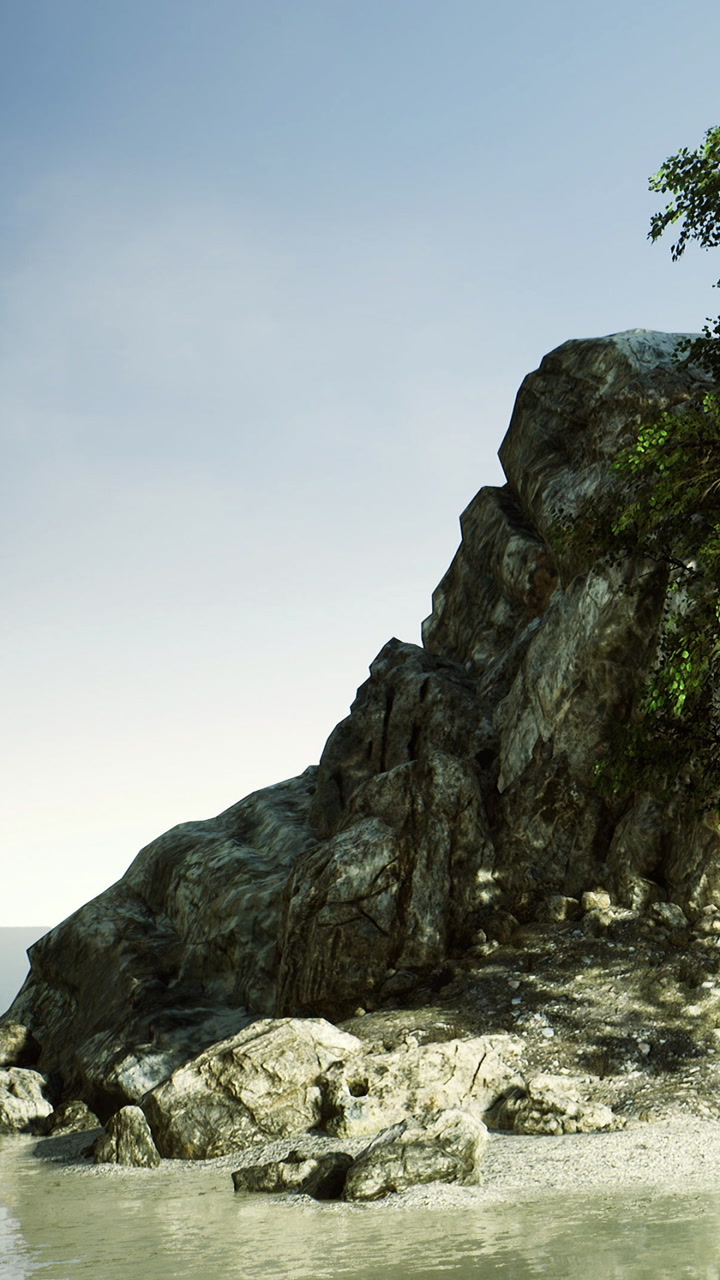 Large rock formation by the shore under blue sky near the sea